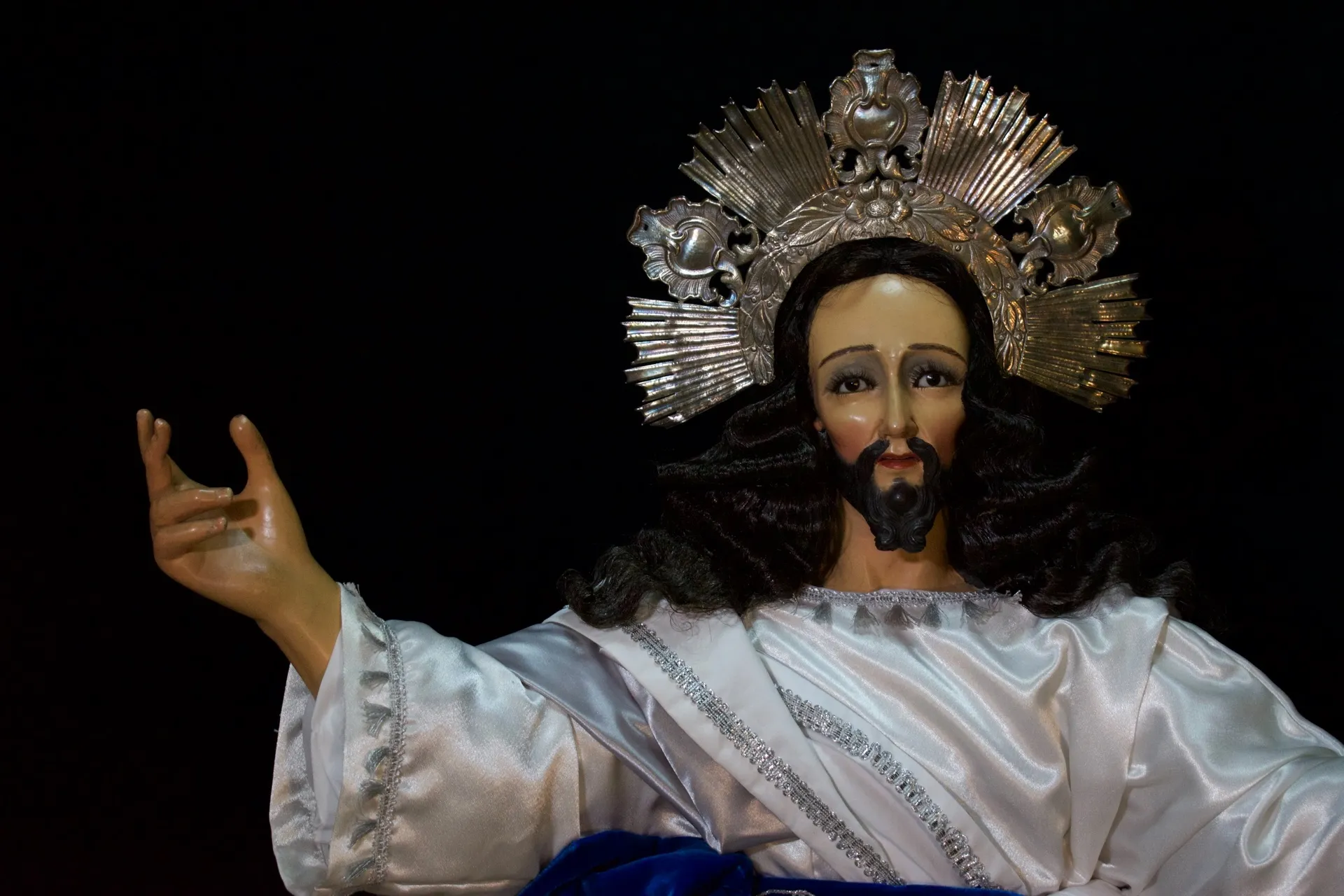 Rostro de Jesús de la Transfiguración de frente, con la mano levantada y el resplandor de plata