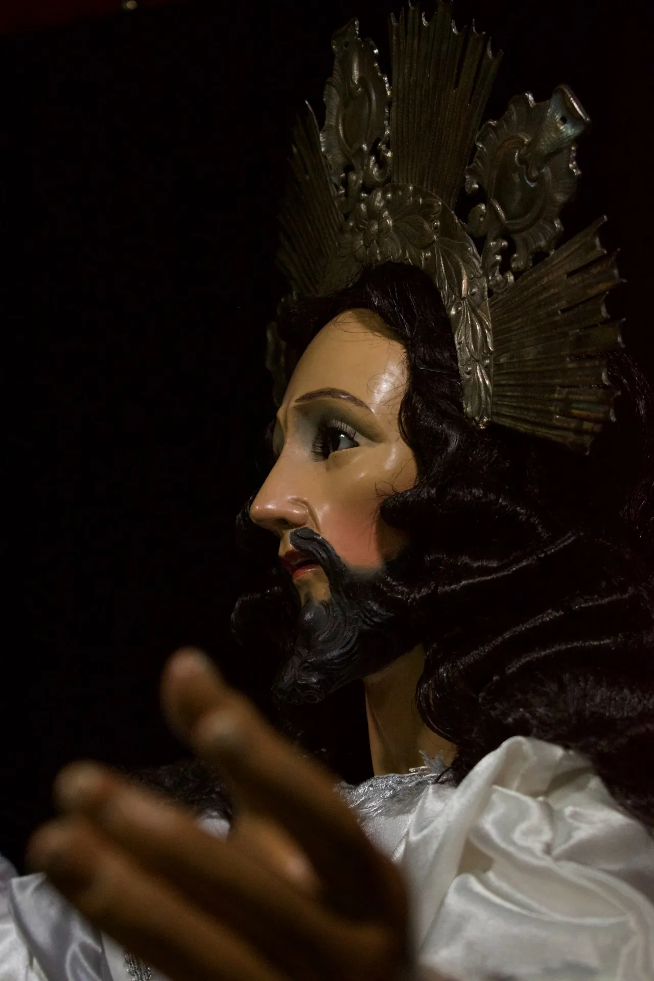 Perfil de Jesús de la Transfiguración con su mano abierta en primer plano, desenfocada
