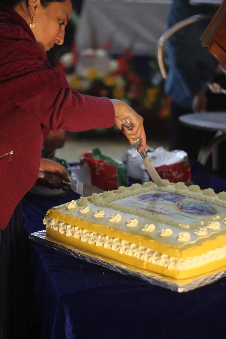 Vecina y devota partiendo el pastel conmemorativo del centenario para compartir con la comunidad