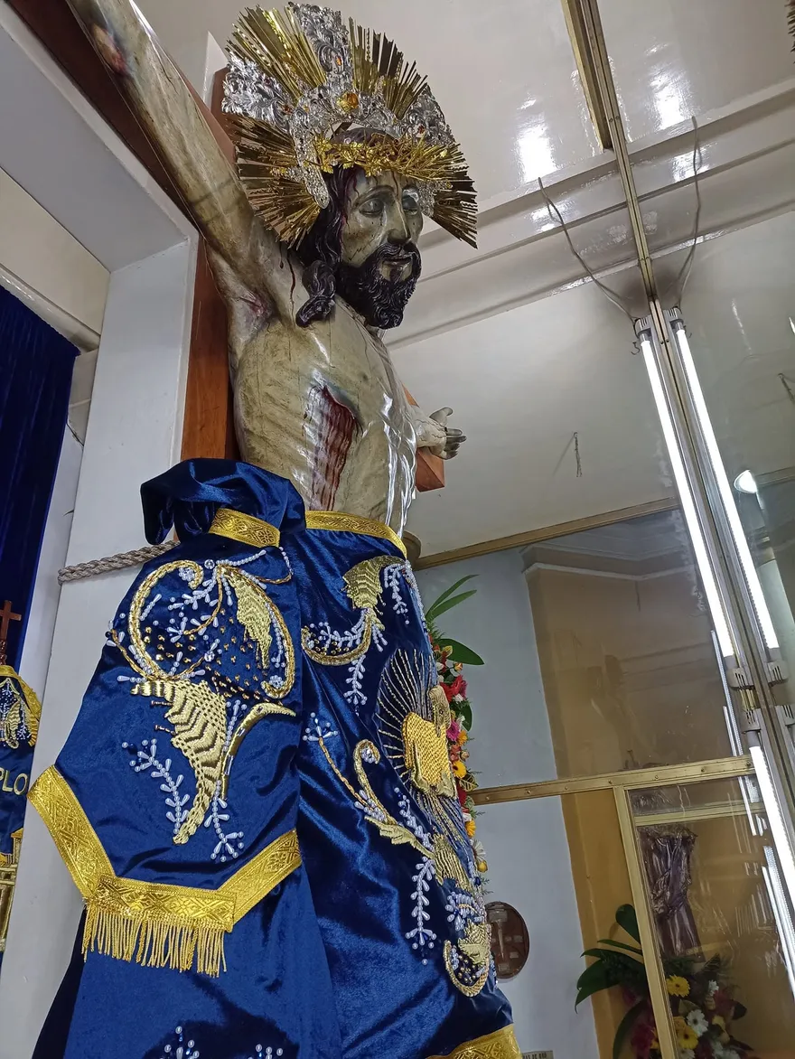Acercamiento en contrapicado al Cristo Crucificado mostrando su resplandor y el bordado dorado de su faldellín