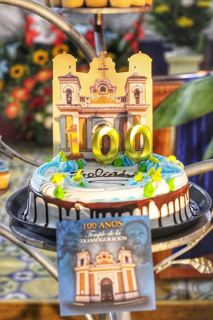 Primer plano de las velas doradas con el número 100 y la réplica de la fachada del templo